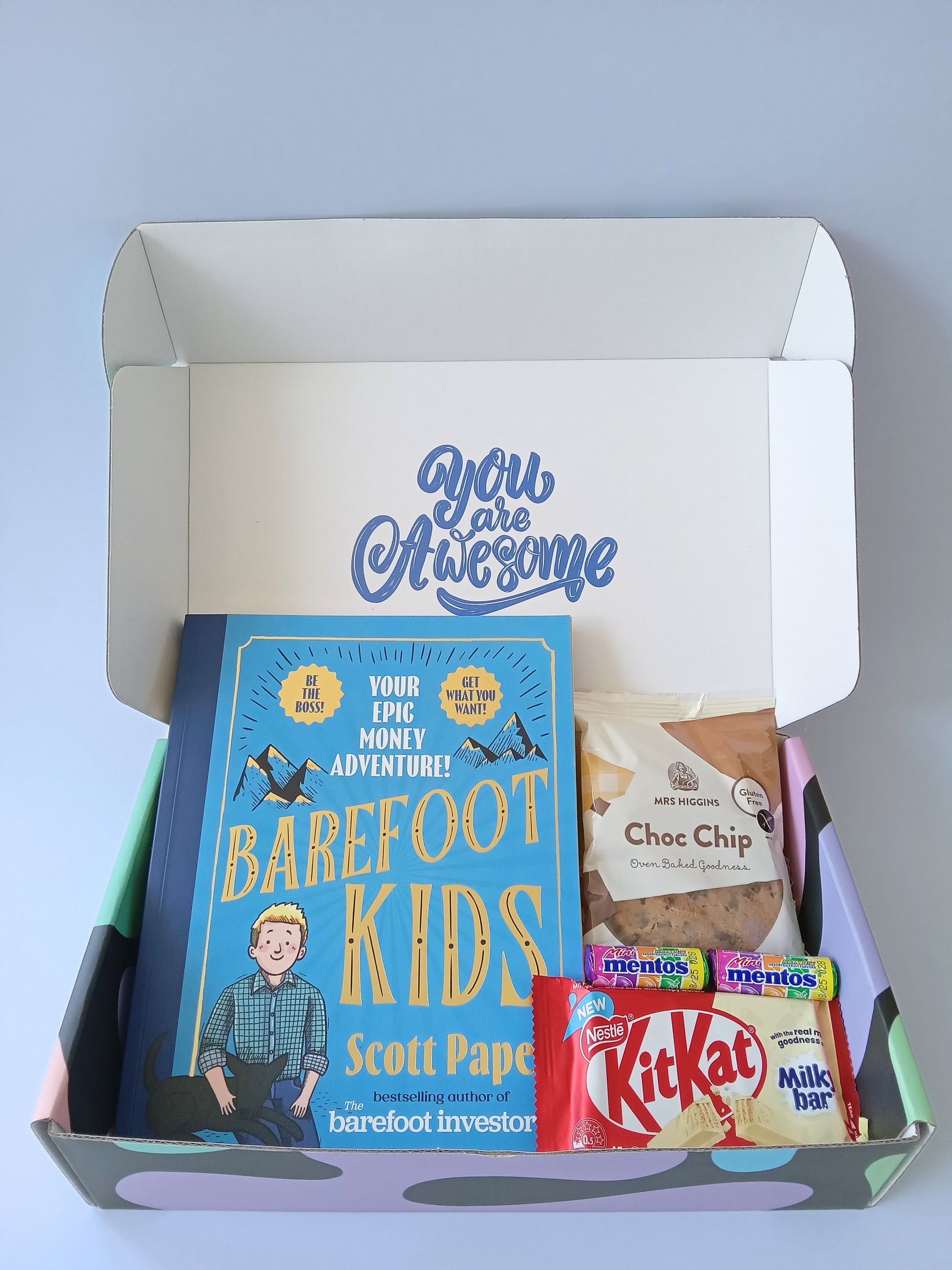 Kids gift box opened with You are Awesome message on the inside of the lid. Gift box containing Barefoot Kids book, Kit Kat, Mrs HIggins Choc Chip Cookie and two mini Mentos rolls multi fruit flavours